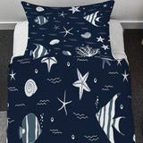 Navy blue bedding set with white sea creature patterns on a bed in a room.